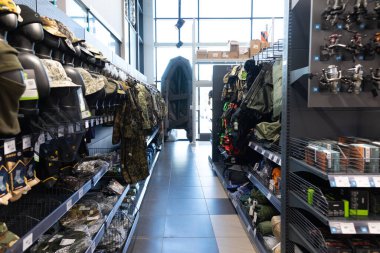 Geniş bir nalbur dükkanında raflar çeşitli tamir aletleri, iş kıyafetleri ve açık hava ekipmanlarıyla doludur. Müşteriler, ev geliştirme ve macera için gereken her şeyi bulabilirler..