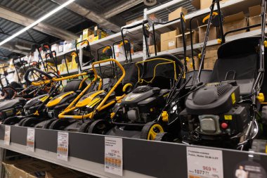 Çoklu çim biçme makineleri bir hırdavatçıda düzgünce sergileniyor, çeşitli modeller ve bahçe bakımı ve müşterilere yardımcı olacak özellikler sergileniyor.
