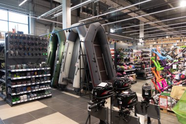 Kalabalık bir hırdavatçıda, müşteriler geniş bir eğlence malzemesi ve araç gereç yelpazesi keşfeder. Raflar şişirilebilir teknelerden bahçe aletlerine kadar çeşitli malzemelerle dolu..