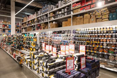 Çeşitli araç gereç ve gereçlerle dolu hareketli bir hırdavatçı. Raflarda elektrikli araçların, aksesuarların ve tamir eşyalarının görüntülerini gösterir.