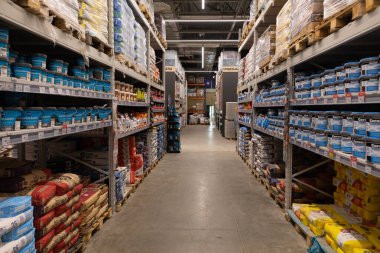 Çimento, boya ve diğer yapı malzemeleriyle dolu sayısız raf gündüz saatlerinde hareketli bir hırdavat ve tamir dükkanının geniş bir koridorunu dolduruyor..