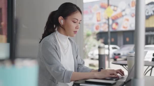 年轻人Gen Z女性亚洲人快乐地在咖啡店的办公室里混合工作打字回复在笔记本电脑上的电子邮件聊天在社交媒体上看到Seo新闻 聪明的亚洲女股票交易员掌握最新技巧 — 图库视频影像