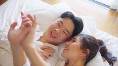 Top view young couple asia people lying down talk on bed relax smile hold hands look at ring on finger. Sweet happy lover asian man woman fall in true love new family life begin just married moment.