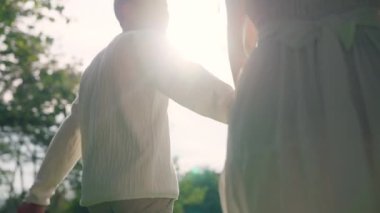 Back rear view young lover asia people happy smile trust hold hand enjoy relax walk way forward to sun light. Just married asian man woman in nature field begin family dream of life love hope and care