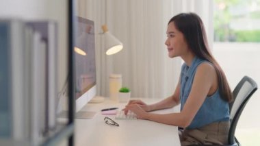 Smart Gen Z tech talent workforce typing SEO sale report on desktop PC happy work easy relax at home office. Remote WFH reskill upskill job MBA study of young people asia woman examine big data graph.