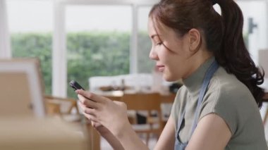 Go green SME owner reply chat comment online talk or set up chatbot on phone. Young seller asia woman typing mobile at home office easy selling CRM platform for eco friendly shop retail net zero store