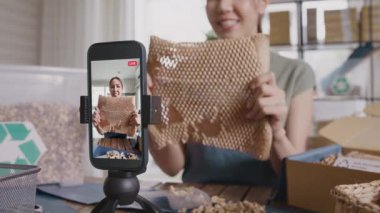 KOBİ 'nin sahibi yeşil net sıfır perakende mağazasından canlı yayında çevre koruma plastiksiz paketleme kutusunu gösteriyor. Asyalı genç kadın tiktok IG bobinli Instagram 'da video kaydı yapıyor..