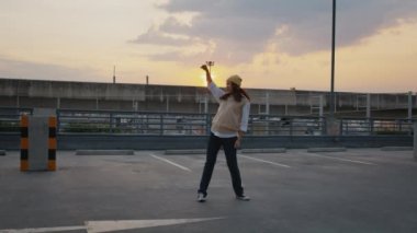 Young active Gen Z asia girl crazy humor fun full length hip hop dance sport at car park lot public metro rail train. Funny people woman happy joy relax in urban city life with sun light enjoy music.