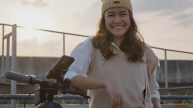 Go green net zero clean low energy eco ride push motor e-scooter. Asia people young woman Gen Z girl happy travel urban city life sun light by modern public metro rail train relax smile look at camera