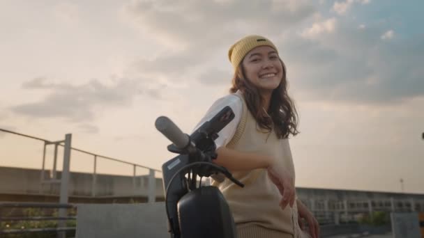 グリーンネットゼロクリーン低エネルギーエコライドプッシュモーター電子スクーターを移動します アジアの若い女性Gen Z女の子幸せな旅行都市生活太陽光によって現代の公共地下鉄の電車リラックス笑顔カメラで見て — ストック動画