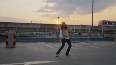 Young active Gen Z asia girl crazy humor fun full length hip hop dance sport at car park lot public metro rail train. Funny people woman happy joy relax in urban city life with sun light enjoy music.