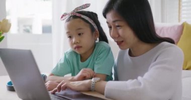 Sevimli Asyalılar alfa küçük Gen Z çocuk sohbeti. Akıllı tablet uygulaması oyunu öğreniyorlar. Annemle evde kanepede. Çocuk bakımında iyi eğlenceler küçük kız ve anne mutlu gülücük rahatla ders çalışmasını online olarak öğret.