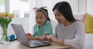 Sevimli Asyalılar alfa küçük Gen Z çocuk sohbeti. Akıllı tablet uygulaması oyunu öğreniyorlar. Annemle evde kanepede. Çocuk bakımında iyi eğlenceler küçük kız ve anne mutlu gülücük rahatla ders çalışmasını online olarak öğret.