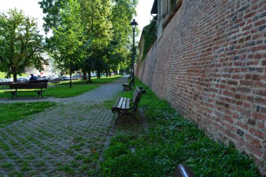 Nostaljik park ve kaldırım manzaraları tuğla duvarlar, taş yollar ve yüksek ağaçlar.