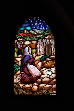 Onil, Alicante, İspanya, 8 Ağustos 2025: Onil, Alicante, İspanya 'daki Santiago Apostol kilisesinde dua eden bir kadınla lekeli cam pencere