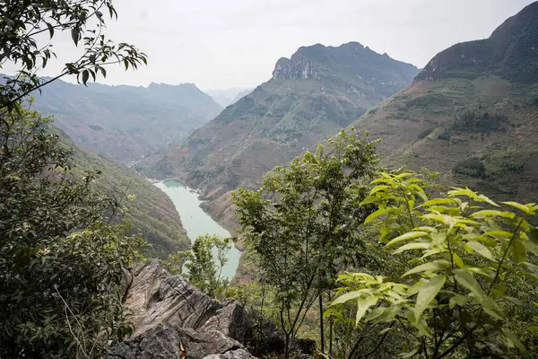 Dağ tepelerinin ortasından akan bir nehir manzarası.
