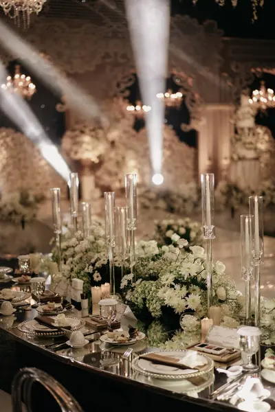 Lüks düğün sofrası süslemesi, beyaz güller, sunak ve arka plan ışıkları.