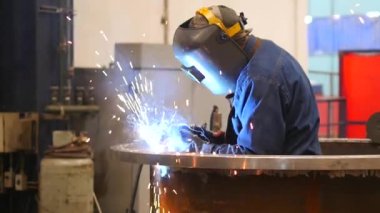 Fabrikada çelik kaynaklamak için kaynak makinesiyle çalışan metal kaynakçı.
