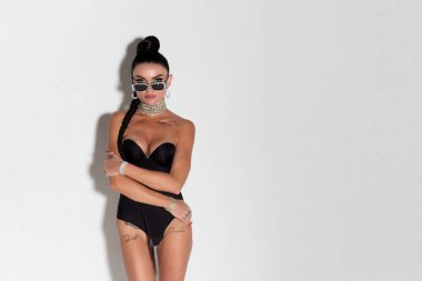 Çekici, narin bir kadın formda vücuduyla hava atıyor ve siyah iç çamaşırlarıyla uzun saçlarını dalgalandırıyor. Hafif ışıklandırılmış stüdyo ortamında cazibesini sergiliyor.