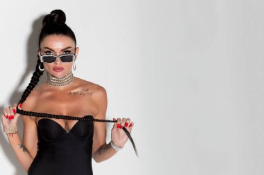 İnce yapılı ve büyüleyici uzun saçlarıyla göz kamaştırıcı bir manken, sıcak bir stüdyo arkaplanına karşı parlak siyah iç çamaşırlarıyla güven saçıyor.