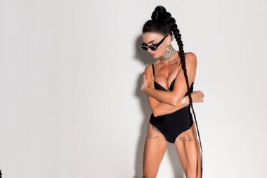 İnce ve tonlu fiziğiyle büyüleyici bir kadın, siyah iç çamaşırlarıyla süslenmiş, ılık tonlu stüdyo ortamında zarafet ve cazibe saçıyor.