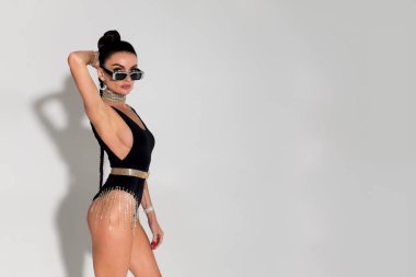 Sıcak renkli bir stüdyoda baştan çıkarıcı bir şekilde soyunan ince bir kadın kendine güven ve cazibe saçar. Gergin vücudu ve zarif at kuyruğu, giydiği şık siyah iç çamaşırlarıyla güzelce tamamlanır.