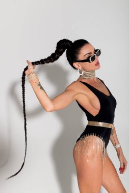 Sıcak bir stüdyonun samimi ortamında, ince bir kadın zarif bir şekilde soyunuyor, büyüleyici vücudunu siyah iç çamaşırlarıyla sergiliyor, uzun at kuyruğu sahnenin cazibesini artırıyor.