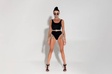 Kendine güveni ve cazibesi yayılan ince bir model, siyah iç çamaşırlarıyla süslenmiş çarpıcı fiziğini, uzun at kuyruğunu ve zerafetini, sıcak stüdyo ışığının büyüleyici sahnesine eklemek için soyunur.