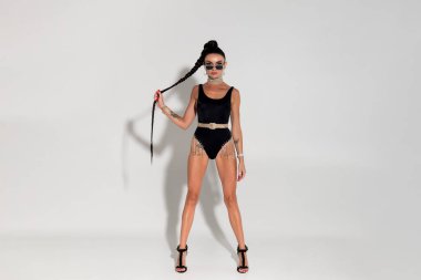 Sıcak renklerle dolu bir stüdyoda şehvetli bir şekilde soyunan ince bir kadın şık siyah iç çamaşırını, gergin fiziğini ve akışkan at kuyruğunu, sofistike ve cazibesini sergiliyor.