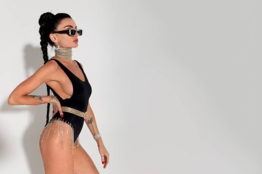 Sıcak renklerle dolu bir stüdyoda şehvetli bir şekilde soyunan ince bir kadın şık siyah iç çamaşırını, gergin fiziğini ve akışkan at kuyruğunu, sofistike ve cazibesini sergiliyor.