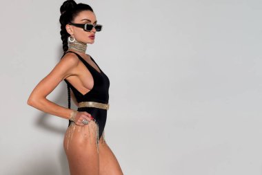 Ateşli esmer, narin vücudunu sergiliyor ve siyah iç çamaşırlarıyla dalgalı kilitler açıyor. Bir stüdyo çekiminde cazibesini sergiliyor. Sıcak tonlarda banyo yapıyor.