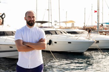 Denizcilik kültürü: Lüks yatıyla limanda poz veren şık bir adam, denizcilik zarafetinin standardını belirler.