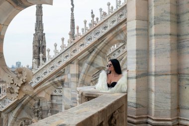 Şık çatı: Işıldayan bir turist kız Milan Katedrali 'nin çatısından beyaz kürkünün içinde zarafet saçarak Milan' ın cazibesini kucaklıyor