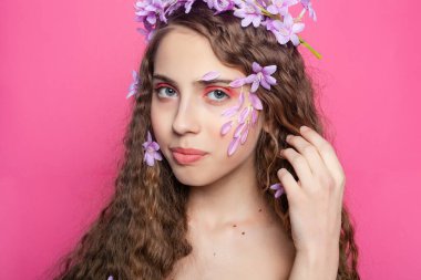 Canlı mor çiçeklerle süslenmiş kıvırcık bukleli bir güzellik. Doğal cazibe ve botanik cazibe hissi uyandırıyor.