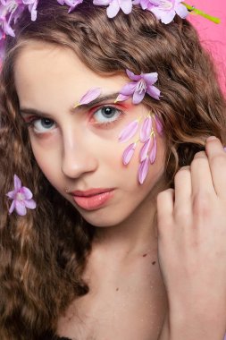 Zarif mor çiçeklerle sarmalanmış parlak bukleler bu kız için çarpıcı bir taç oluşturuyor. Zarafet ve kadınlık yayıyor.