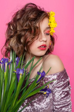 Doğayı kucaklayan genç bir bayanın büyüleyici görüntüsü, yüzü narin pembe bir arka planda narin bir sarı çiçekle örtülmüş. Güzelliği ve zarafeti ifade etmek için ideal..