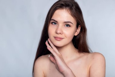 Temiz tenini şefkatle okşayan genç bir kadının görüntüsüyle basitliğin güzelliğini keşfet. Güzellik malzemeleri ve kozmetik reklamları için mükemmel..