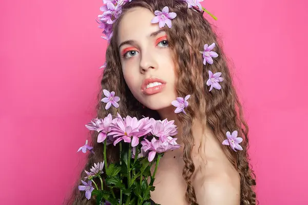 卷发装饰着精致的紫色花朵 为这个女孩创造了迷人的容貌 抓住了花朵的美丽和女性的本质 图库图片