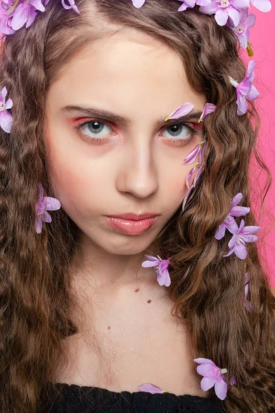 エレガントなガールは 繊細な紫色の花で飾られた彼女のカーリーロックを展示し 花の配置で魅力的でロマンチックなオーラを除きます ロイヤリティフリーのストック写真
