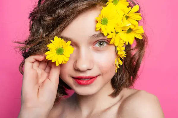 一个面容柔和的女人的浪漫画像 她的脸部分被一朵黄色的花掩藏在粉红色的背景下 适合以爱情为主题的设计和诗意表达 免版税图库照片