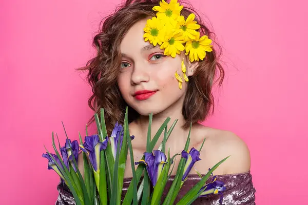 柔らかい特徴を持つ少女のロマンチックな肖像画 彼女の顔は部分的にピンクの背景に対して黄色の花で覆われています 無邪気さと魅力を伝えるのに最適 ストック写真