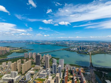 Jiangxia Bölgesi, Wuhan, Çin 'de Tangxun Gölü' nü yakalayan panoramik hava görüntüsü, geniş şehir binalarını ve durgun su üzerinde berrak gökyüzünü gösteriyor ve köprüleri birleştiriyor..