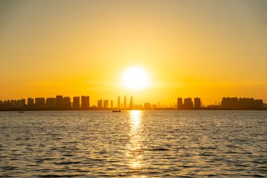 Güneş ışığı Çin 'in Wuhan şehrinin ufuk çizgisi yakınlarındaki sıcak bir akşamda suyu yansıtır..