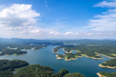 Suizhou City, Hubei, Çin 'de açık mavi bir gökyüzünün altında geniş bir göl manzarasını noktalayan yemyeşil adalar..