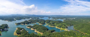 Durgun mavi sulardan yükselen yeşil ormanlık adalar Suizhou, Hubei, Çin 'de barışçıl bir doğal manzara oluşturur..