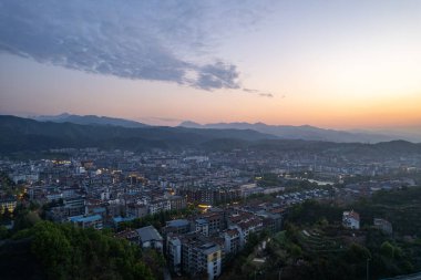Çin 'deki Wudang kasabasının panoramik manzarası, şafak vakti görkemli dağların arasına kurulmuş binalarını ve ışıklarını gözler önüne seriyor..