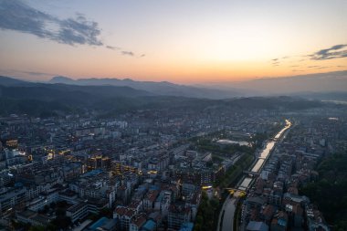 Gün batımında Çin 'deki Wudang kasabasının havadan görünüşü dolambaçlı bir nehir ve uzak dağlarla şehir manzarasını gözler önüne seriyor..