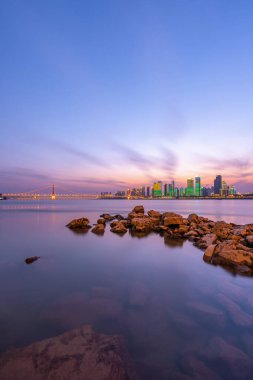 Şehrin ışıkları alacakaranlıkta suyla birlikte köprü..