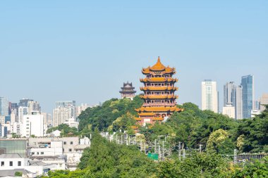 Sarı Turna Kulesi yeşil ağaçların ve modern binaların arasında duruyor..