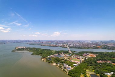 Wuhan şehri Çin manzarası açık mavi gökyüzünün altında binalar ve yemyeşil ağaçlarla geniş bir nehre bakıyor..